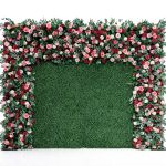 Green hedge wall with floral border frame of pink and white blooms, garden-style backdrop panel for weddings and photo booth setups.