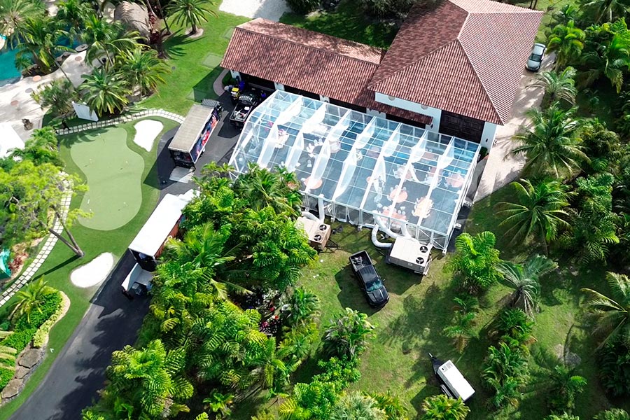 High-angle view of a clear-span marquee tent with HVAC cooling units attached for guest comfort.