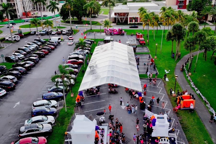 Large clear-top party tent covering multiple parking spaces for a community festival.