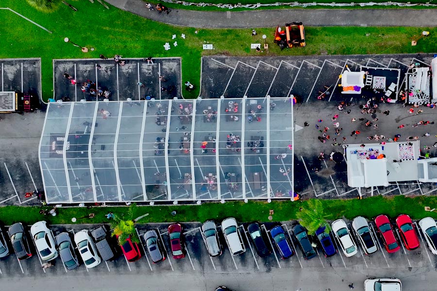 Aerial view of a massive clear span event tent with guests and nearby inflatables.