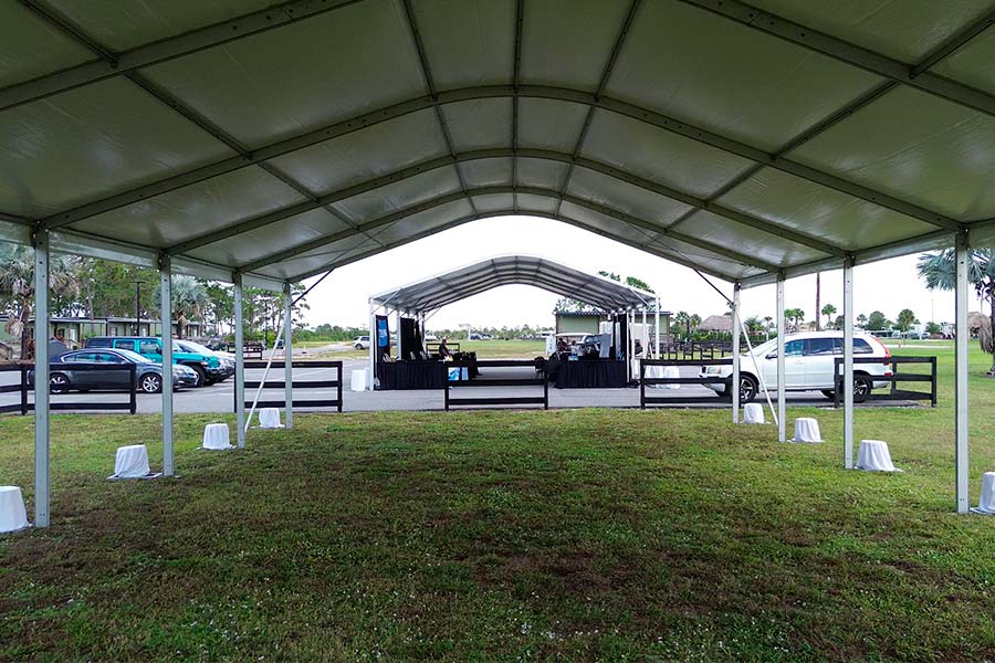 Interior view of a long white arched frame tent showing the open floor space and structural support beams.