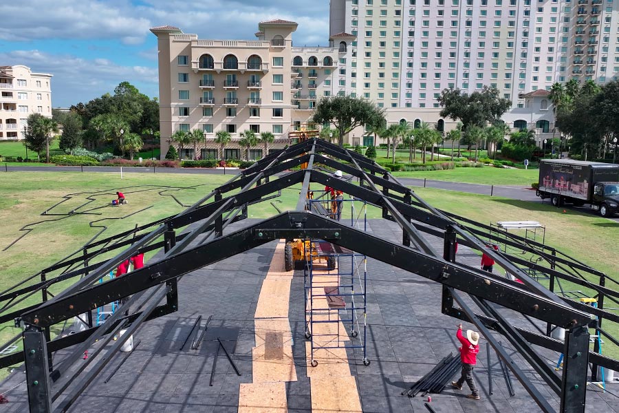 Construction of a black steel frame wedding tent structure on a modular outdoor floor.