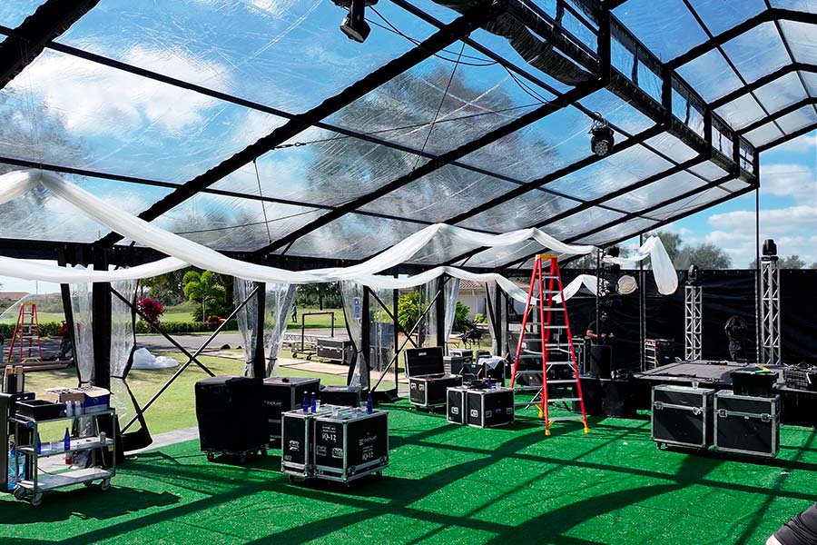 Professional event equipment and stage lighting inside a clear-span party tent with decorative fabric.