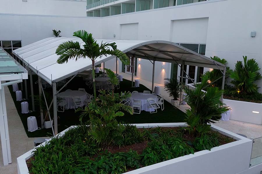 20x30 white event tent setup outdoors for a reception with round tables and white chairs.