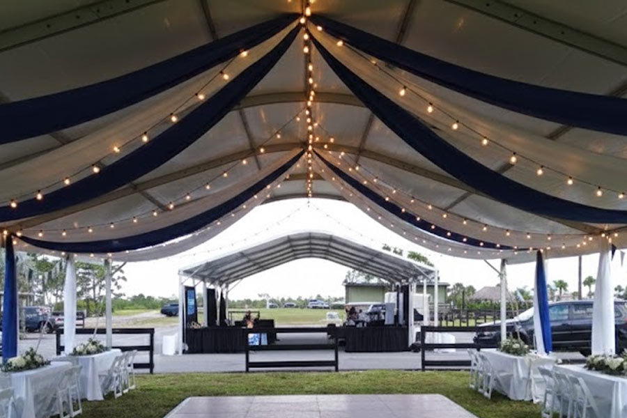 Interior of a clear tent with pink and white furniture, showing setup of event accessories.