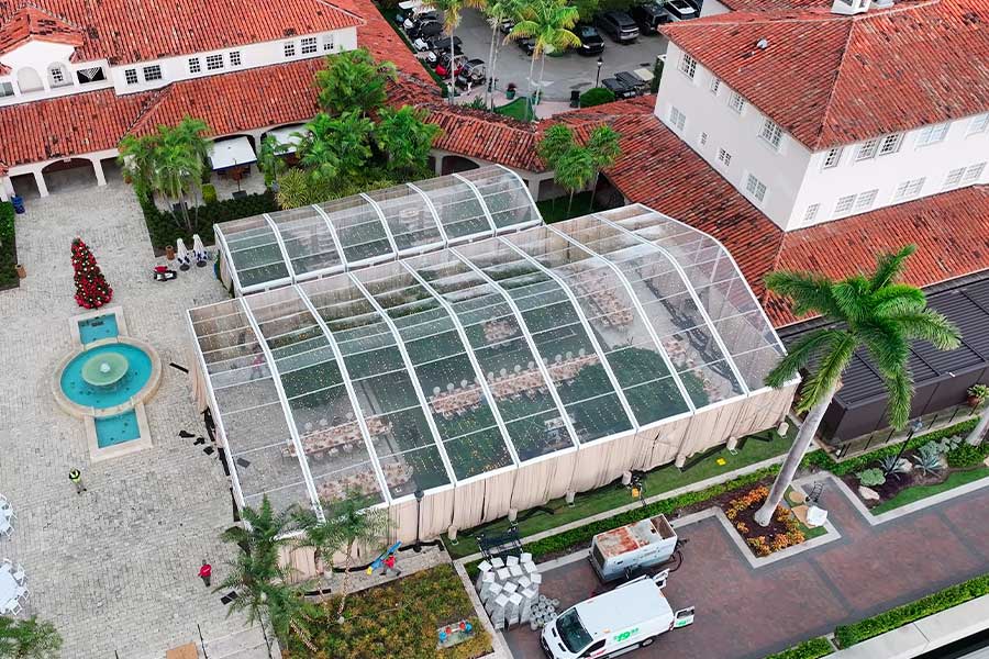 Aerial view of a large clear span event tent next to a luxury resort with Spanish-style architecture.