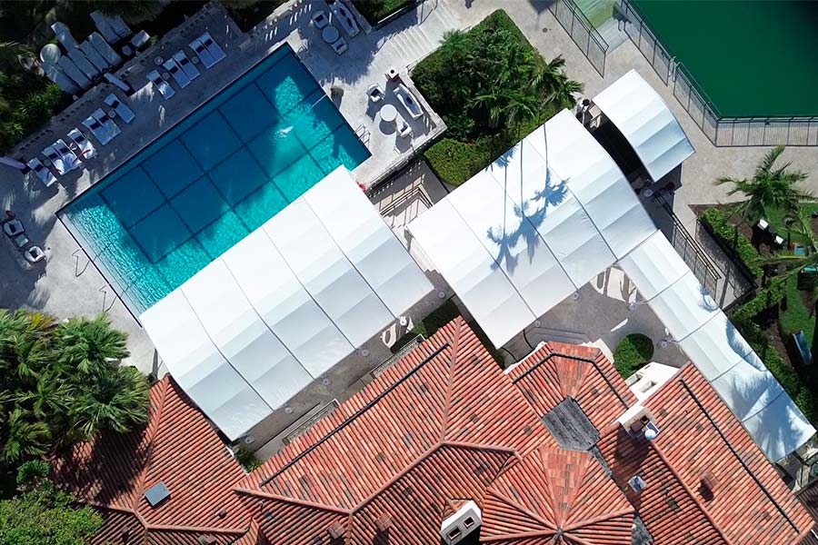 Aerial view of large white event tents installed over a swimming pool and patio area.