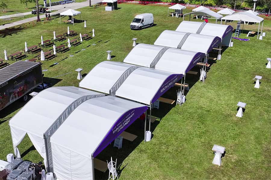 Modular white curved tents with purple accents for a health and wellness event or outdoor exhibition.