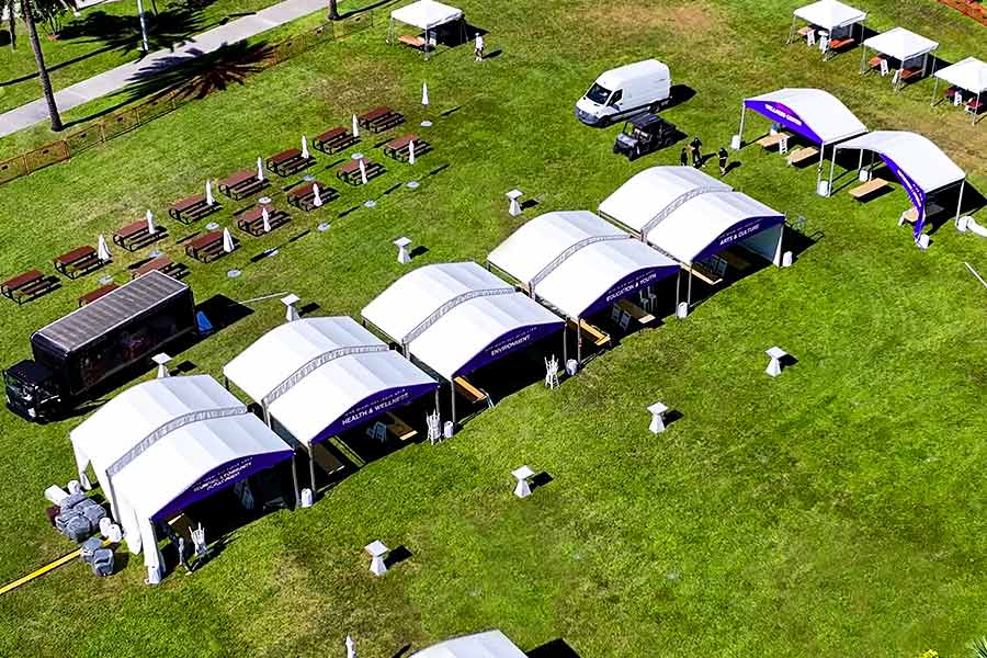 Multiple curved tents on a field for various event sponsors and a trailer-truck nearby.