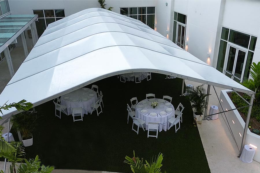 Large white event canopy tent set up on an artificial turf patio, ideal for a family celebration dinner.