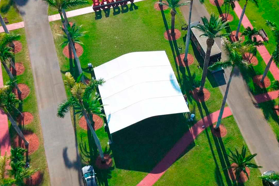 White event tent set up on a beach with rows of chairs for a wedding ceremony and wooden aisle.
