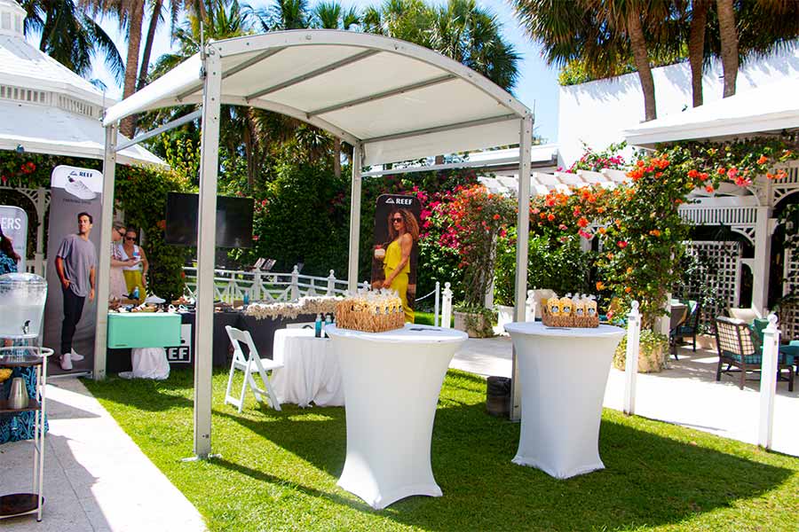 Compact white tent for brand activation display at garden event surrounded by flowers.