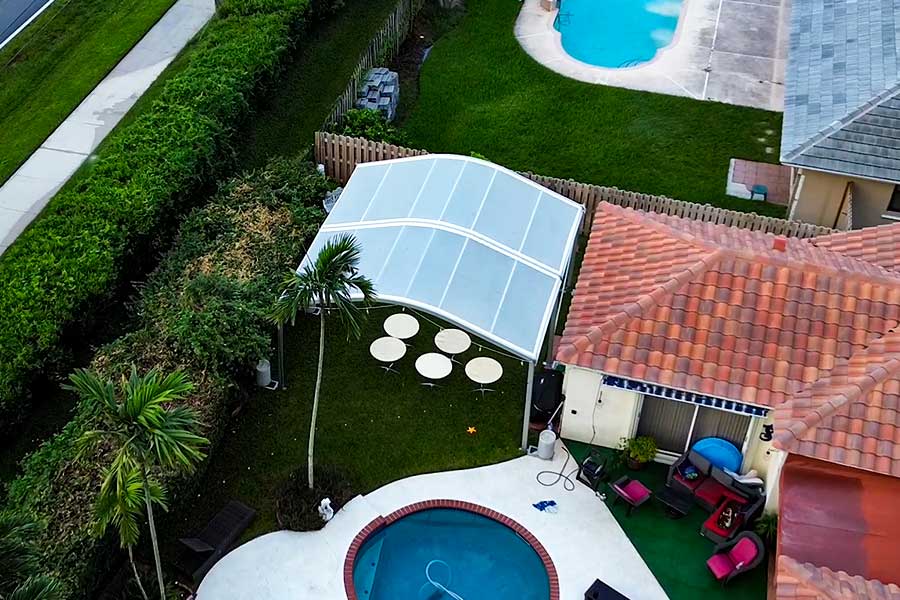20x20 clear curve tent over a lawn area with patio furniture near a pool, perfect for private events.