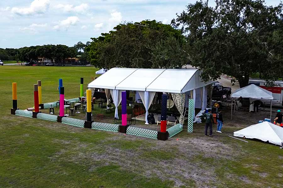 Aerial view of a clear curve tent next to a red-tiled house and pool for a backyard celebration.