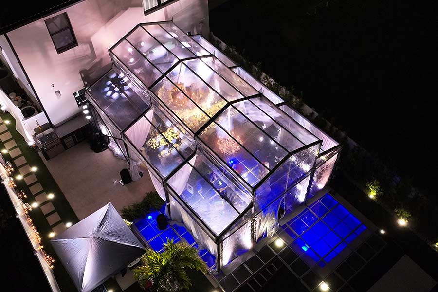 Clear roof event tent at night with vibrant blue and warm yellow decorative lighting for a party.
