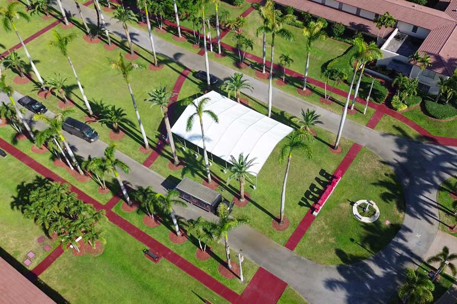 Aerial view of a white curved tent providing weather protection on a tropical driveway.