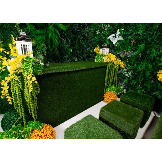 Grass ottoman covered in green artificial turf with cube shape, versatile lounge footrest or seat rental for outdoor events.