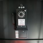 Black luxury telephone booth with glass panel doors and red interior flooring, photo booth-style event rental.