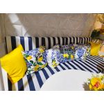 White throw pillow with repeating lemon branch print and blue tile border, fresh coastal accent cushion for outdoor lounge and event décor.