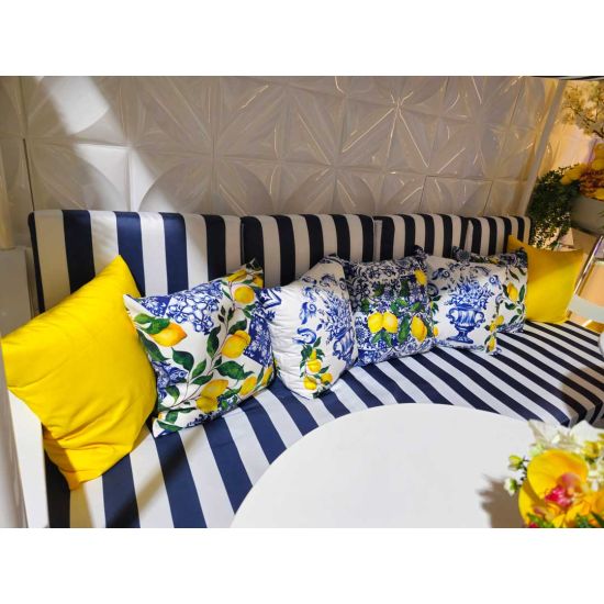 White throw pillow with repeating lemon branch print and blue tile border, fresh coastal accent cushion for outdoor lounge and event décor.