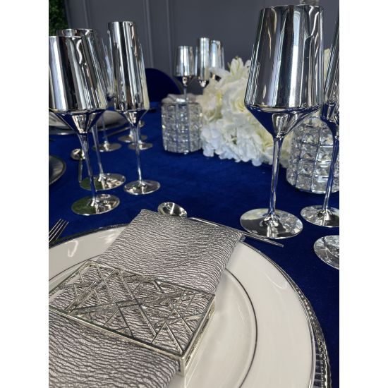 Geometric napkin holder with gold metal open-frame cube design holding a folded white cloth napkin, modern accent for event table settings