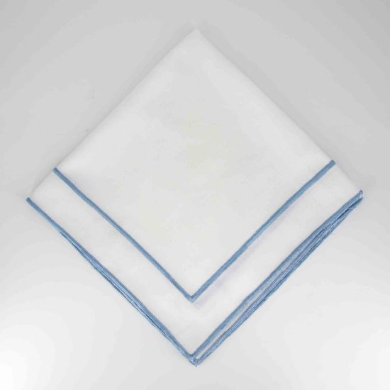 White Monarch napkin with blue border trim detail, folded in a triangle on a white plate for coastal weddings and elegant event settings