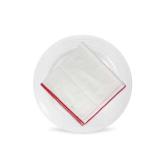 White napkin with red stitched trim border, folded in a triangle on a white plate for festive weddings and classic event table settings