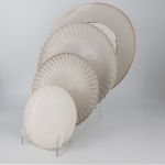 Bone-colored petal-rim salad plate with scalloped edge and sunburst ridged design, medium round plate on a white background
