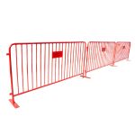 Red metal crowd control barrier with vertical bars and stabilizing feet, portable safety barricade for event lines, restricted areas, and venue security