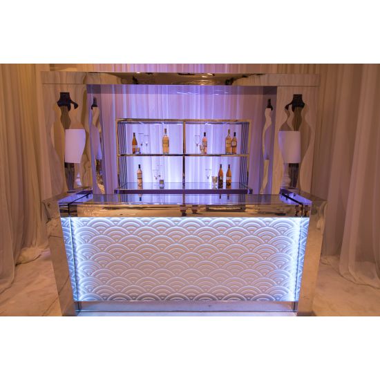 Small Reflection Bar Set compact mirrored front with curved panels, matching arched back bar with glass shelves, styled with white florals and candles.