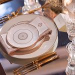 White dinner plate with thin gold rim and geometric gold line pattern around the edge, large round plate on a white background