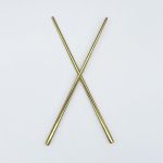 Pair of modern gold chopsticks crossed on a white background, sleek reusable tableware for sushi, Asian cuisine, and upscale event dining.