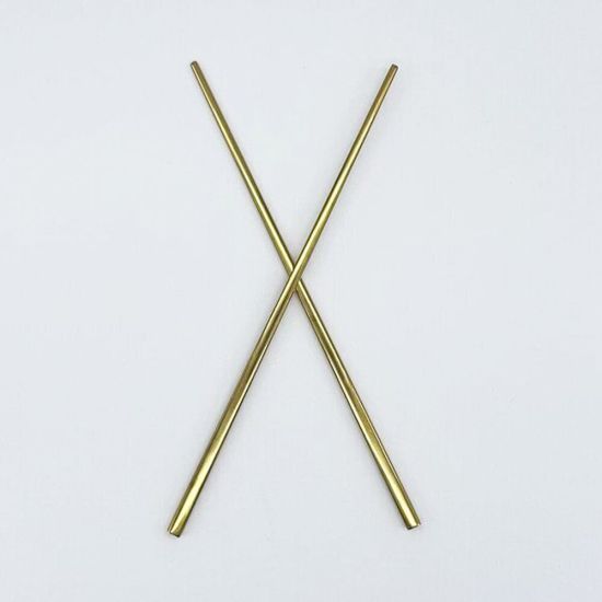 Pair of modern gold chopsticks crossed on a white background, sleek reusable tableware for sushi, Asian cuisine, and upscale event dining.