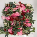 Green hedge wall with floral border frame of pink and white blooms, garden-style backdrop panel for weddings and photo booth setups.