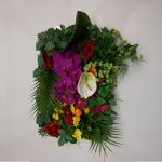 Green foliage wall backdrop with bright mixed flowers and tropical accents, colorful photo backdrop panel for parties and event décor.