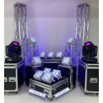 Event uplighting package with truss towers, moving head lights, and LED fixtures on road cases, stage lighting setup for weddings and parties.