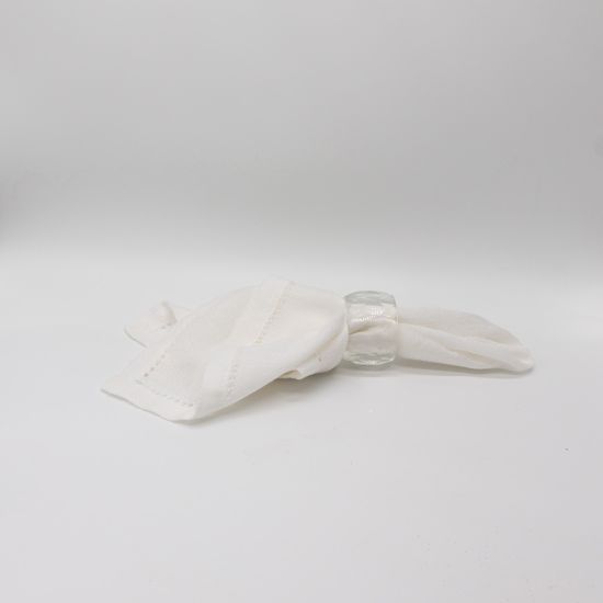 Large crystal cut napkin ring with faceted clear design holding a folded white cloth napkin, glamorous table accessory for wedding and formal event place settings