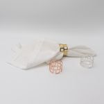 Cube-style napkin ring with modern geometric design holding a folded white cloth napkin, sleek table accent for weddings and formal events