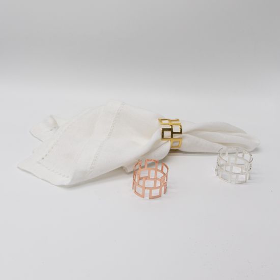 Cube-style napkin ring with modern geometric design holding a folded white cloth napkin, sleek table accent for weddings and formal events