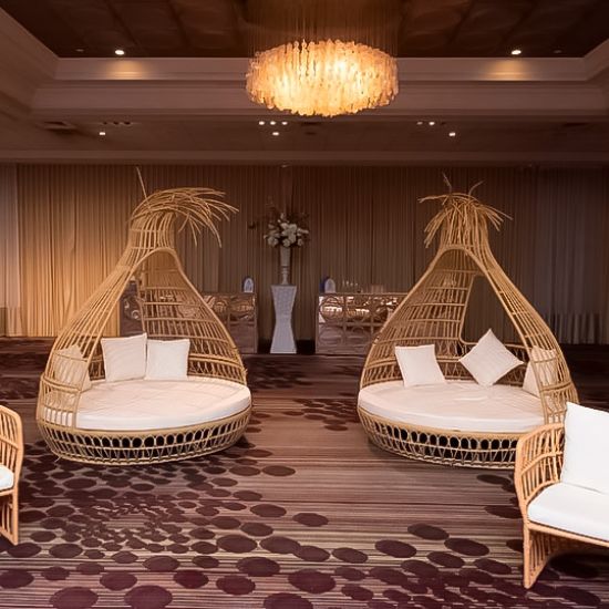 Bohemian wicker bed with teardrop canopy frame and cream cushion, statement lounge bed rental for boho weddings and outdoor events.