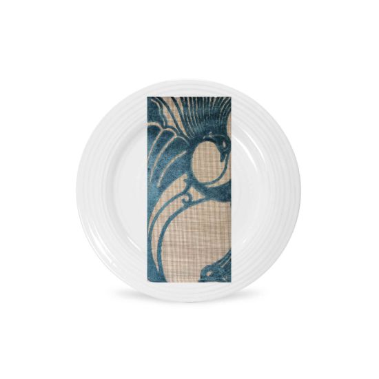 Pacific peacock napkin with blue feather-style print and woven texture, folded on a white plate for coastal wedding and event tables