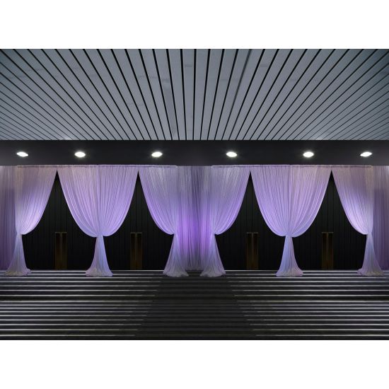 Purple drape entrance backdrop with simple gathered panels and uplighting, clean pipe-and-drape entry design for weddings and events.