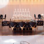 Gold trident accent armchair with smooth upholstery, curved back, gold-trim side cutouts, and sleek gold metal legs for luxury event lounge seating.